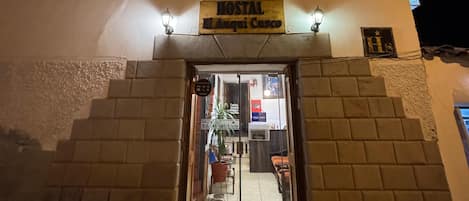 A hostel with a sign reading "HOSTAL El Augui Cusco" at night.