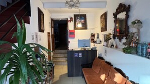 A living room with a sofa, a coffee table, a potted plant, and a staircase leading to another room. - Hostal El Auqui (Cusco)