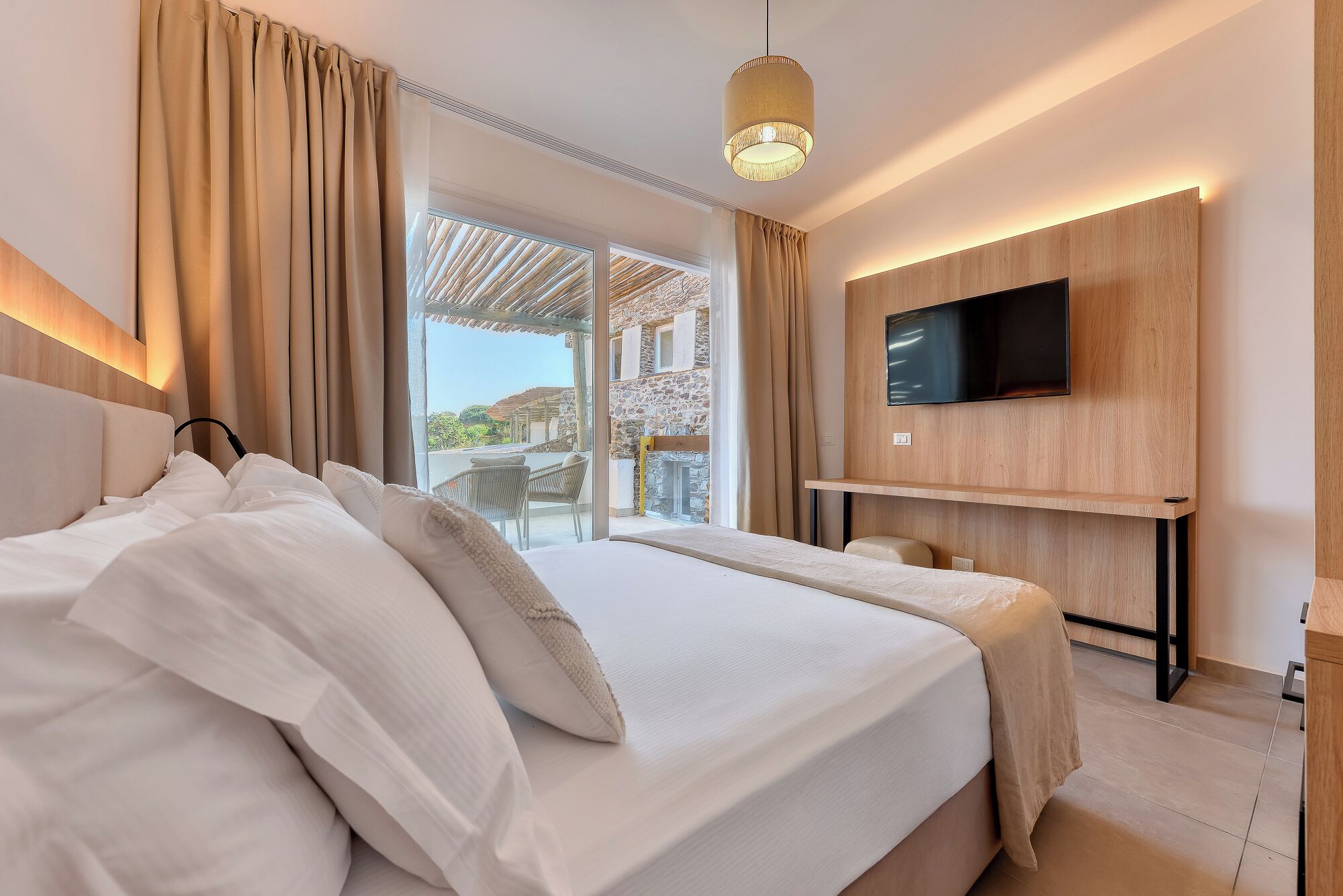 Ein Hotelzimmer mit einem Bett, einem an der Wand befestigten Fernseher und Blick ins Freie.