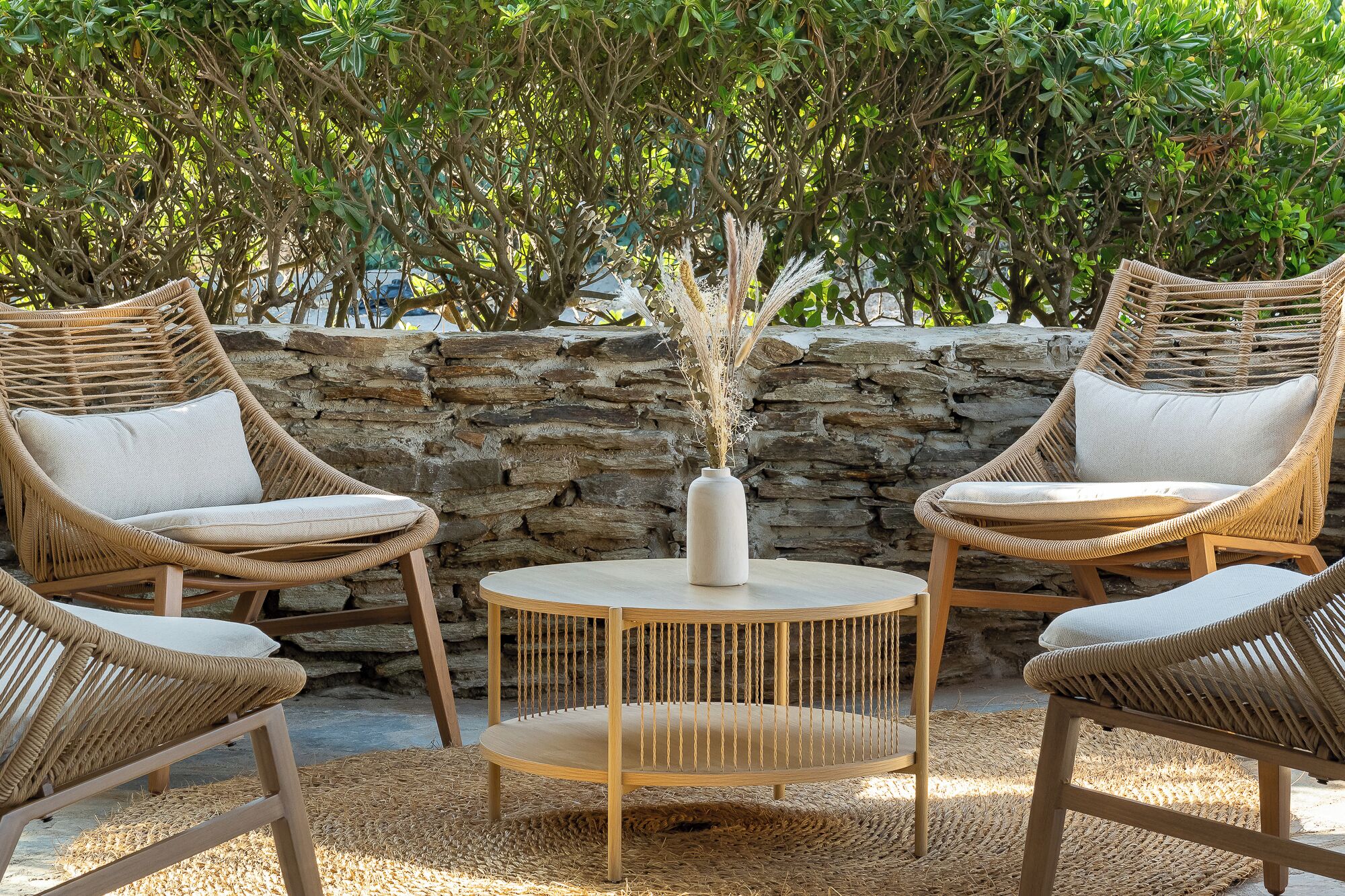 A wicker outdoor seating area with a stone wall backdrop and a central table.