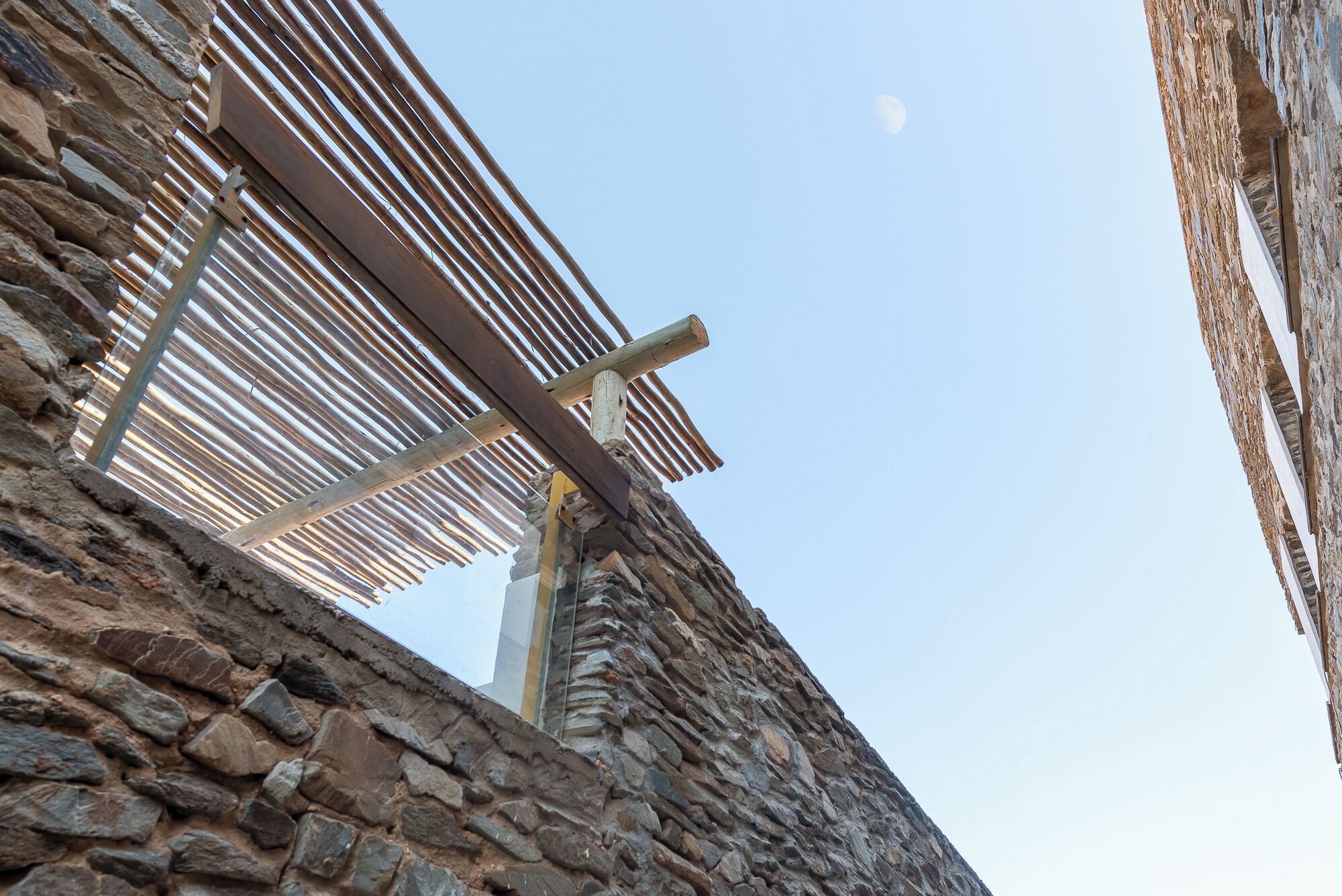 A stone building with a wooden pergola structure.
