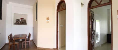 Zona pranzo con tavolo e sedie in legno, un quadro appeso al muro e una porta che dà su un'altra stanza.