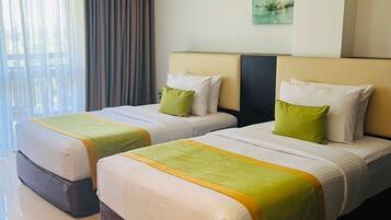 Habitación de hotel con dos camas, un ventanal con cortinas, aire acondicionado instalado en la pared y un cuadro.