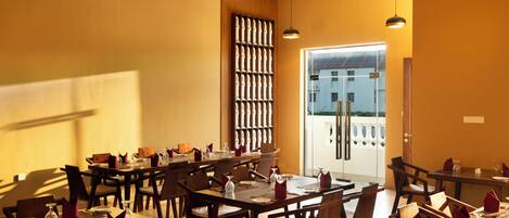 A restaurant with multiple tables and chairs, a large window, and a door leading outside.