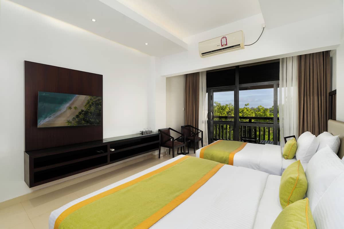 A hotel room with two beds, a TV mounted on the wall, a desk, and a balcony with a view.