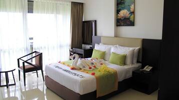 Habitación de hotel con una cama, un escritorio, una silla, un teléfono y un cuadro en la pared.