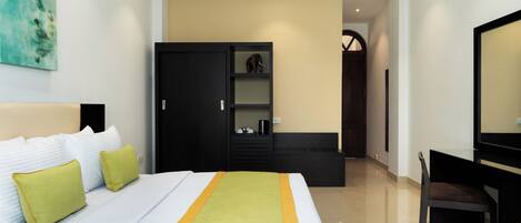 Una habitación de hotel con cama, escritorio, armario y espejo.