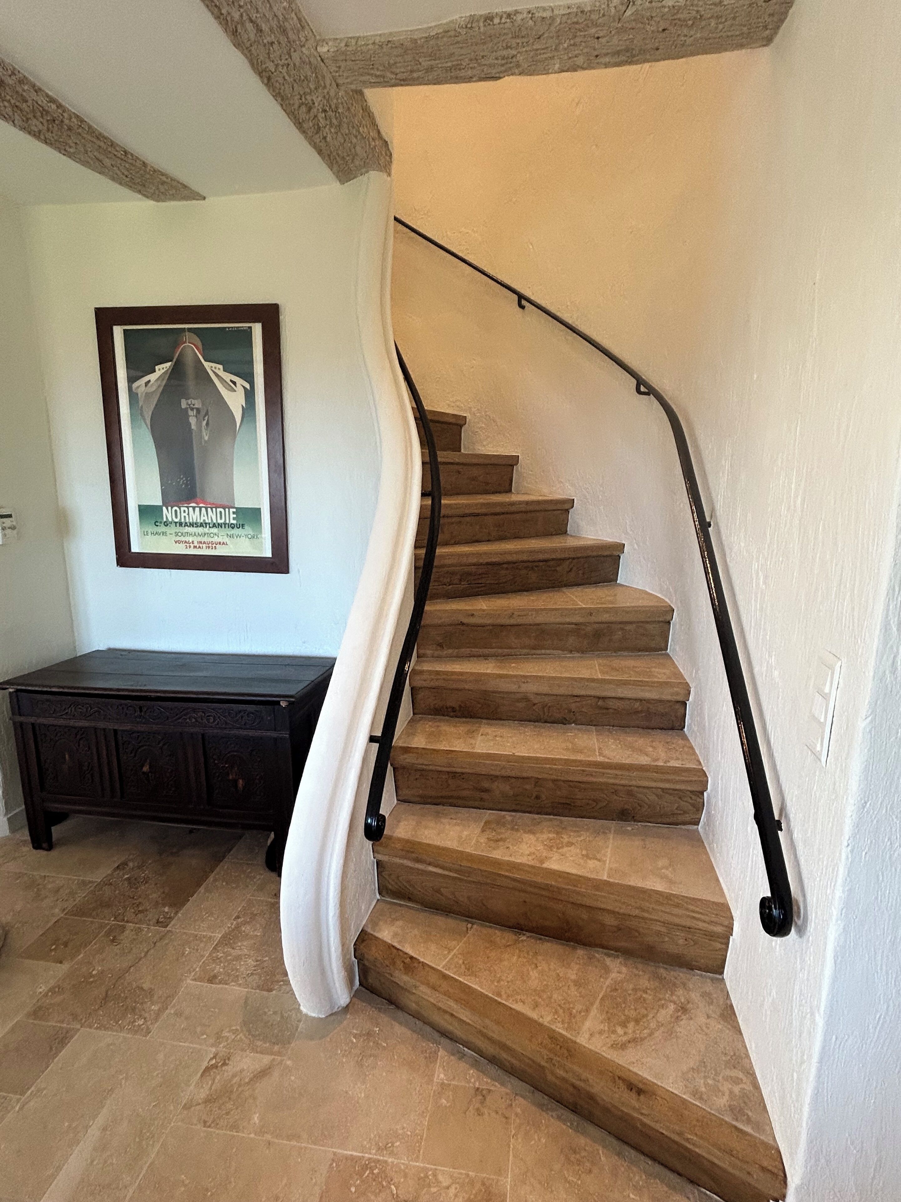 A wooden staircase with a white handrail and a dark wooden bench below.