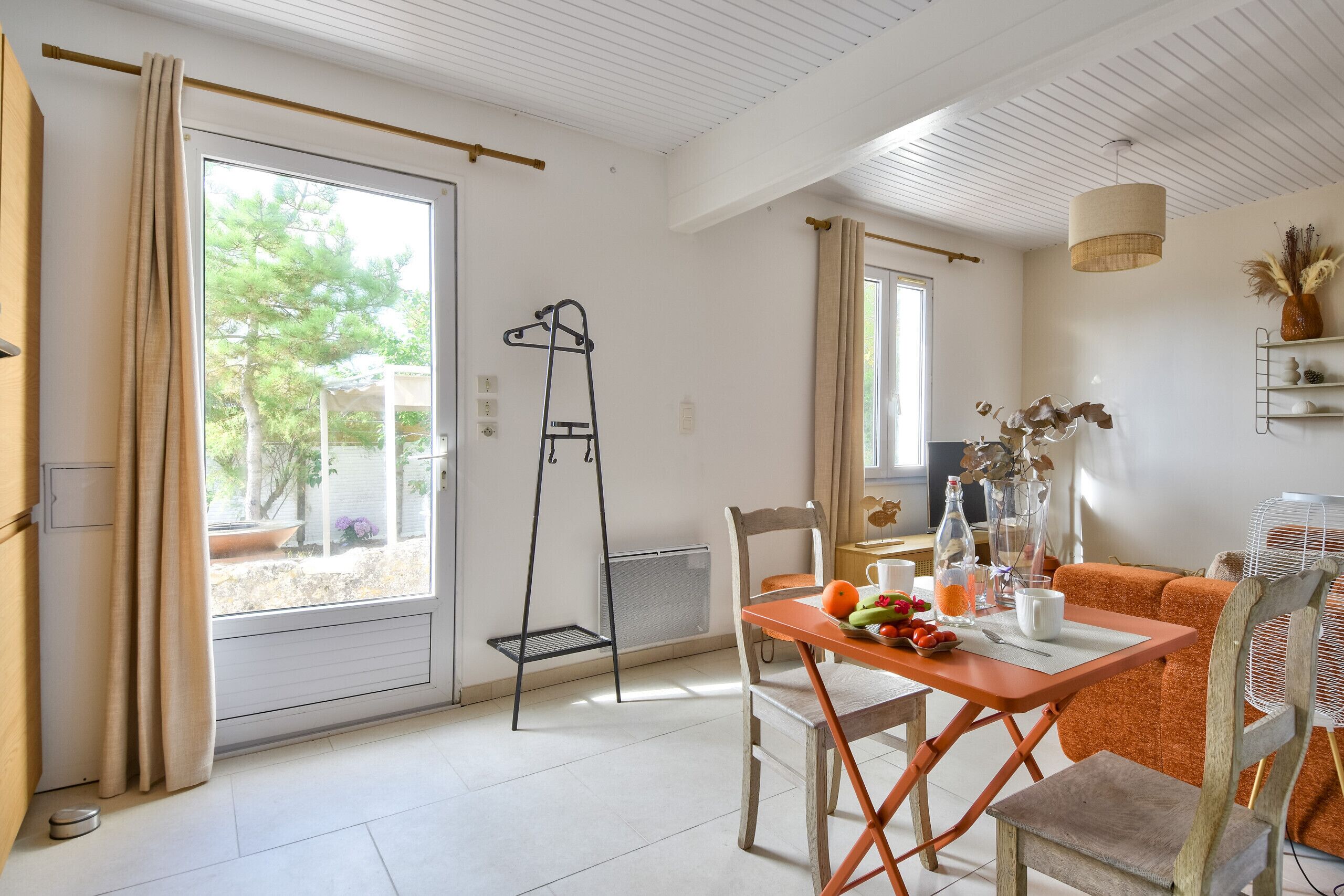 Una habitación luminosa con una mesa, sillas y un ventanal con cortinas.