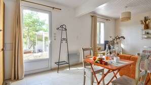 A bright room with a table, chairs, and a window with curtains.