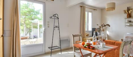 Una habitación luminosa con una mesa, sillas y un ventanal con cortinas.