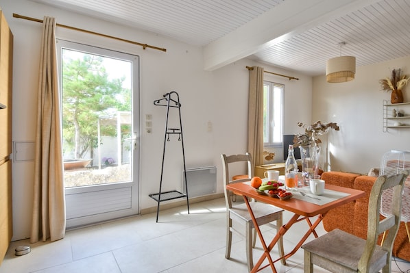 A bright room with a table, chairs, and a window with curtains.