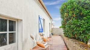 A wooden deck with two lounge chairs and a potted plant.