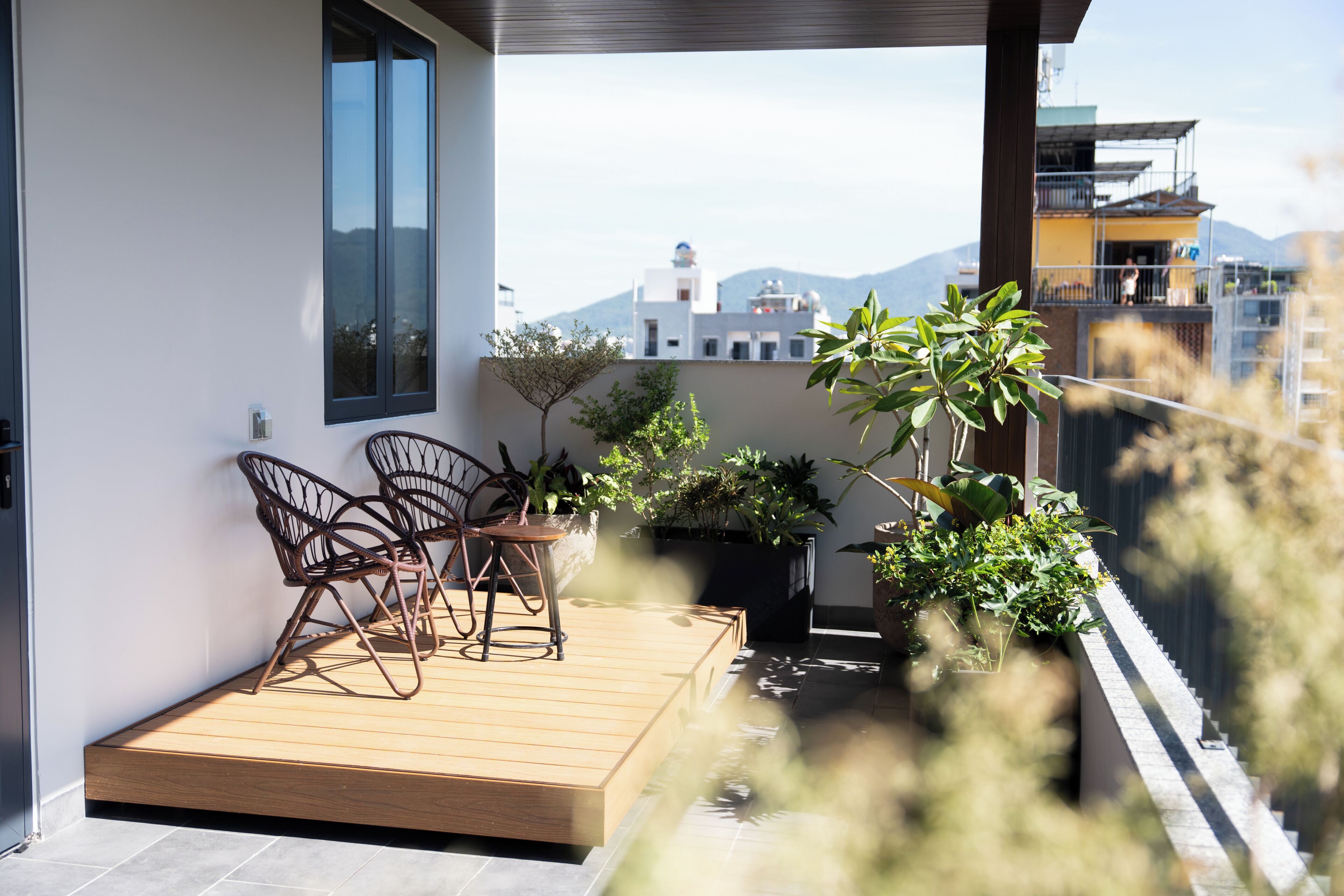 A balcony with a wooden deck, chairs, and potted plants.
