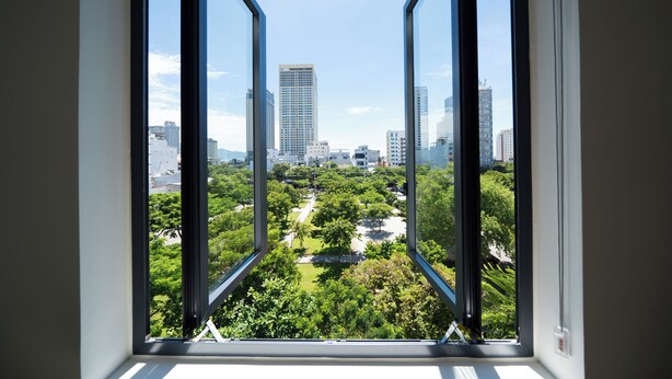 A view through a window of a cityscape with buildings and a park. - Sam Hotel & Apartment Da Nang (Da Nang)