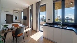 A modern apartment with a dining area, kitchen, and large windows offering a city view. - Sam Hotel & Apartment Da Nang (Da Nang)