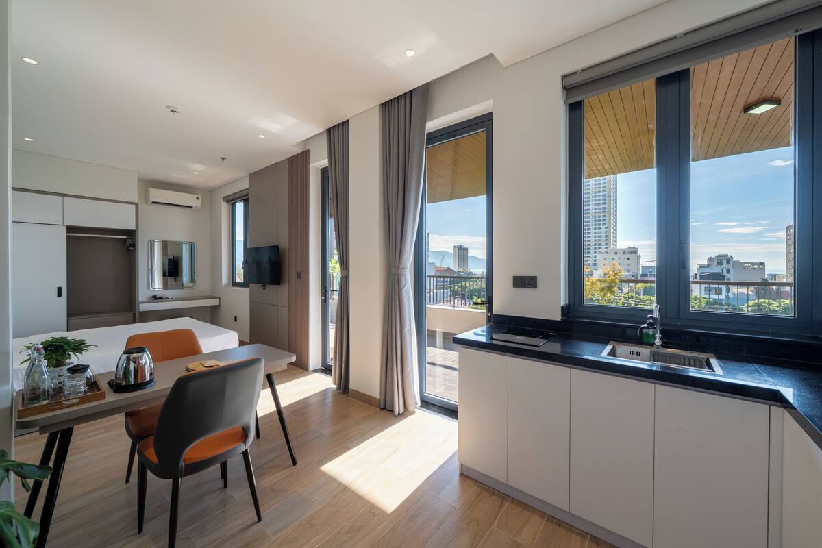 Un apartamento moderno con comedor, cocina y ventanas amplias que ofrecen vista a la ciudad.