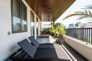A balcony with two black wicker lounge chairs, a wooden ceiling, and a view of the cityscape. - Sam Hotel & Apartment Da Nang (Da Nang)