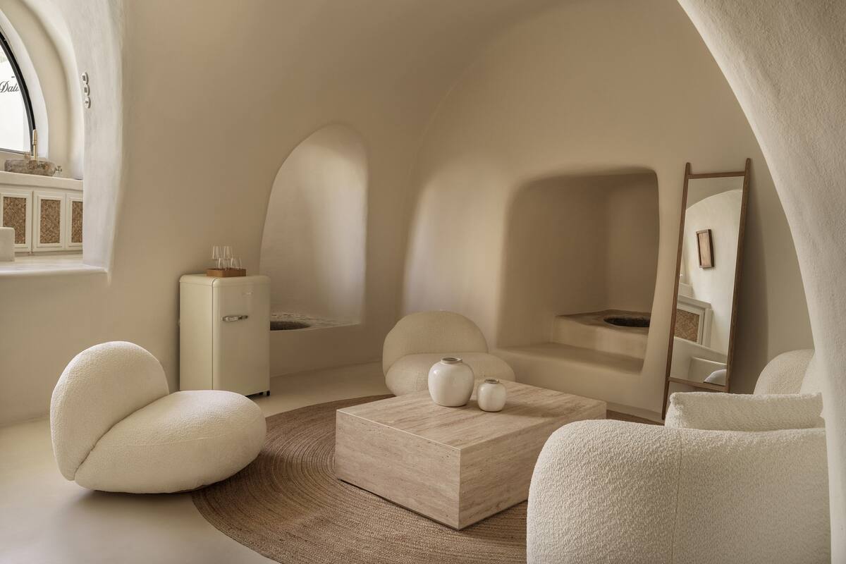 Una habitación moderna y minimalista con un techo curvo singular, una mesa de centro de madera y un espejo grande.