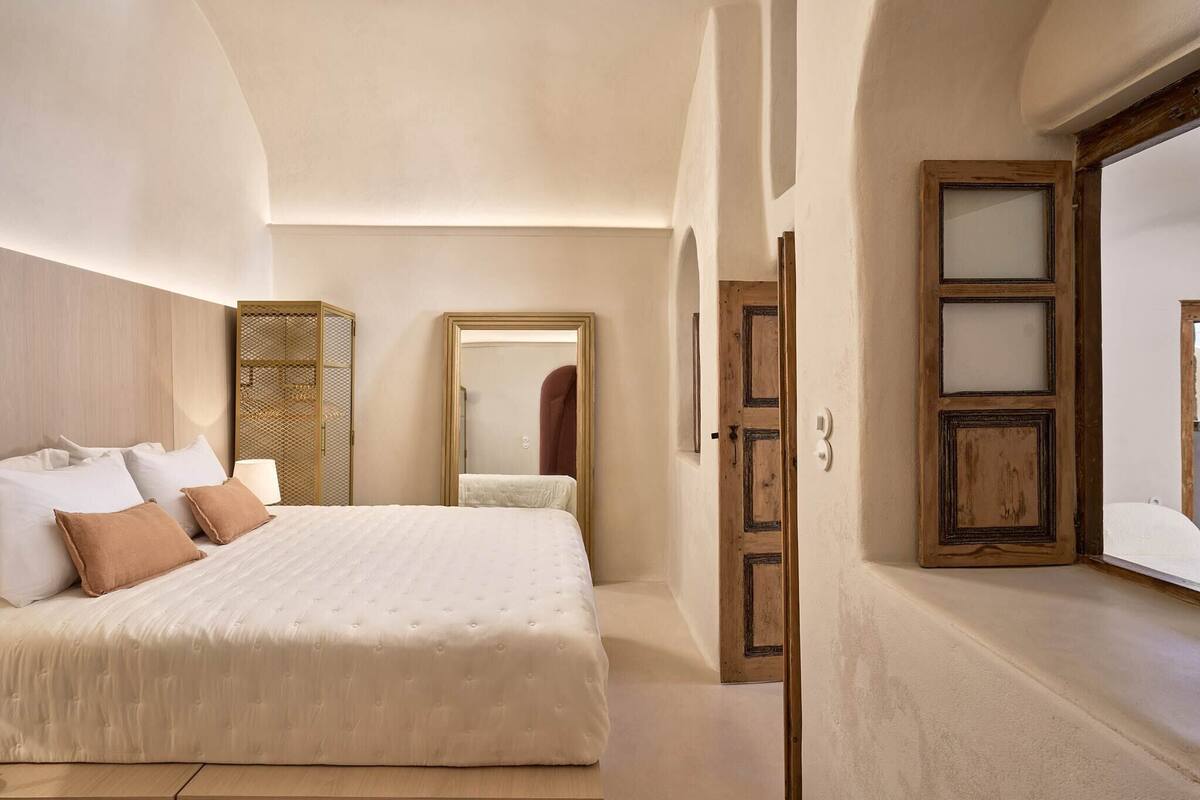 Un dormitorio con una cama grande, un armario, un espejo y una puerta.