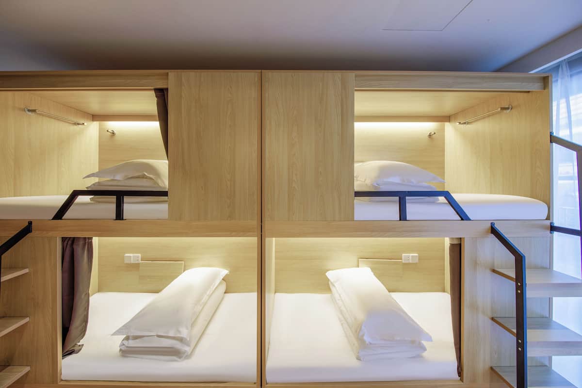Une chambre avec des lits superposés, des murs en bois et des barreaux en métal.