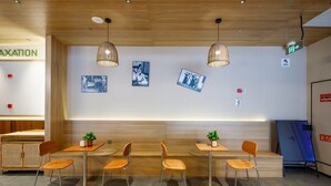 Un intérieur moderne avec un plafond et des murs en bois, des tables avec des chaises et des tableaux accrochés aux murs.