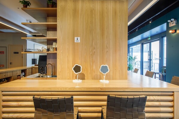 Una cocina moderna con encimeras de madera, una isla central con dos taburetes y vistas a la calle a través de amplias ventanas.
