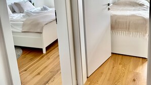 A modern hotel room with a wooden floor, a bed with white bedding, and a white door. - "Discover Comfort and Relaxation at Strandsegler Heiligenhafen!" (Heiligenhafen)
