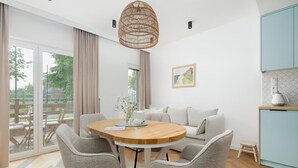 Un comedor moderno con una mesa redonda de madera, sillas tapizadas en gris y una lámpara colgante de fibras naturales.