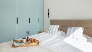 Un dormitorio con cama, almohadas, una mesita de noche, una bandeja con cosas para el desayuno y un armario.