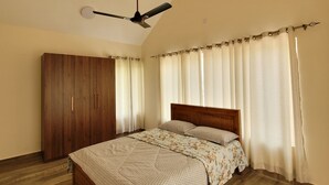 A bedroom with a bed, wooden wardrobe, and a ceiling fan. - The Ark Haven Ooty (Adikaratti)