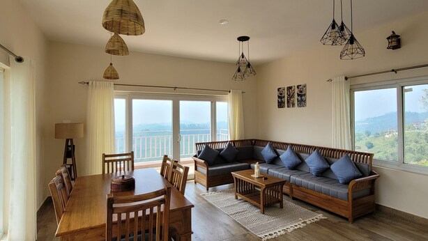 A spacious living room with a wooden dining table, a sofa set, and hanging pendant lights. - The Ark Haven Ooty (Adikaratti)
