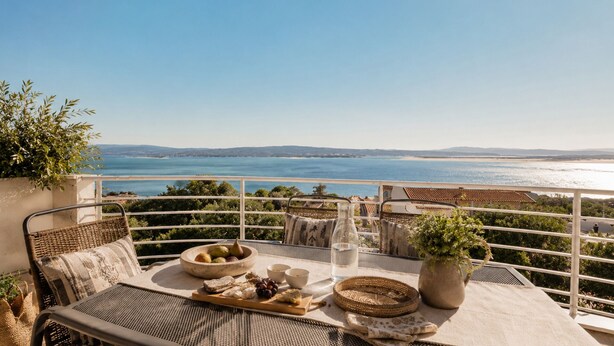 Un balcone con un tavolo apparecchiato per un pasto, con vista sulla costa.