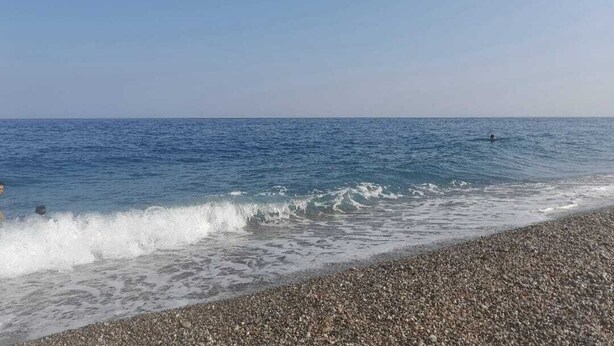 Ein Strand mit Kieselsteinen und Wellen.