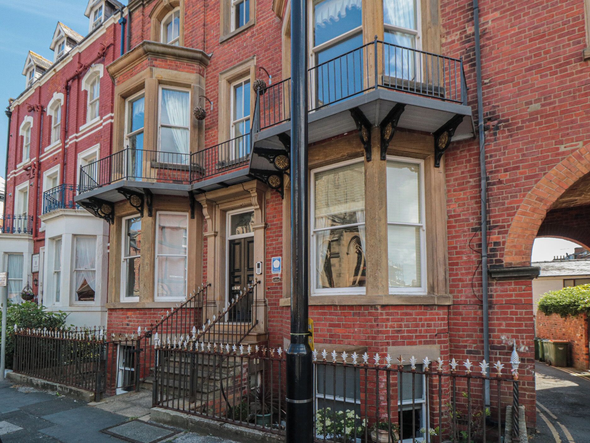 A red brick building with bay windows and a black metal fence.