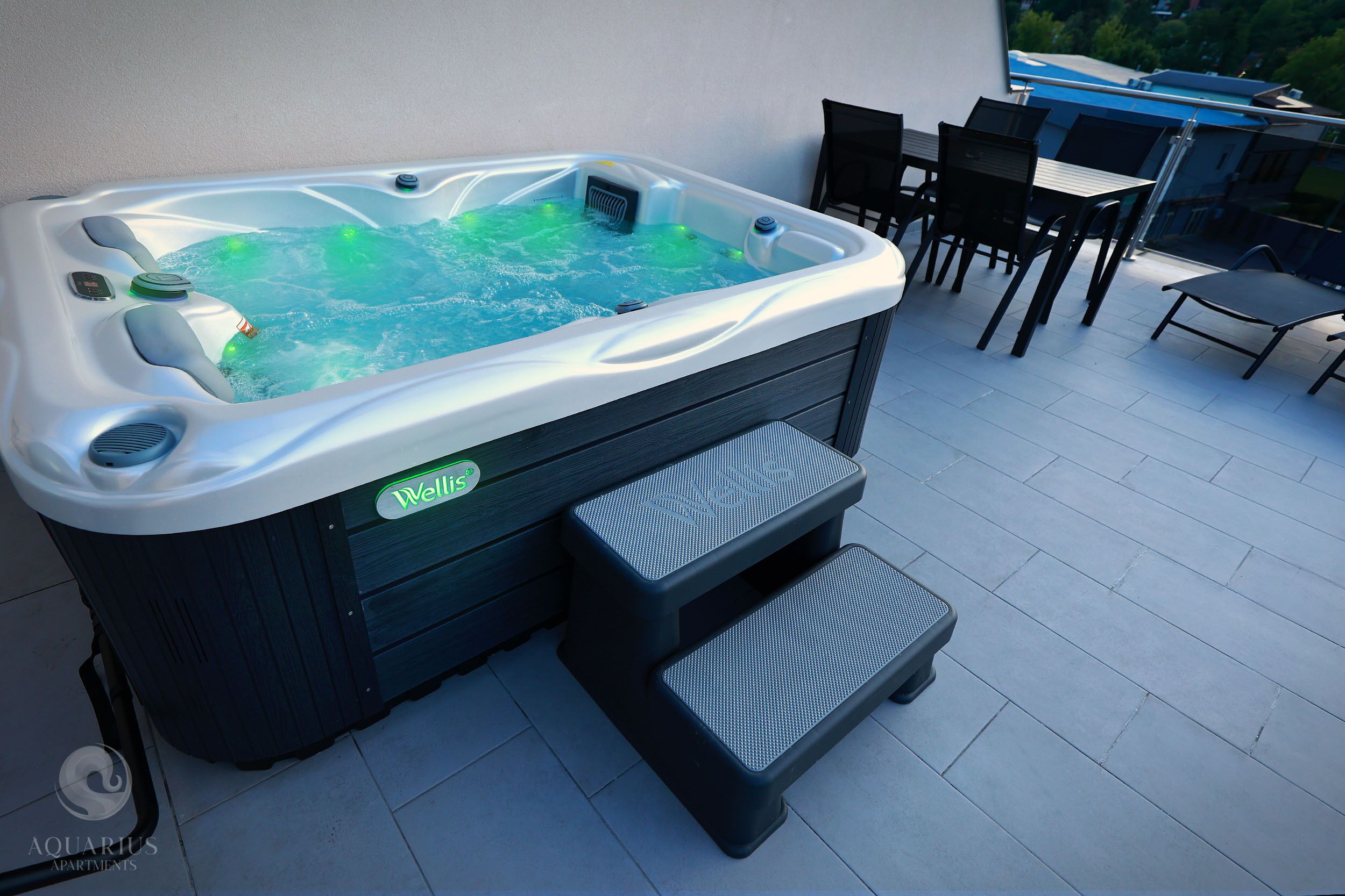 A hot tub with a control panel, steps, and a chair nearby.