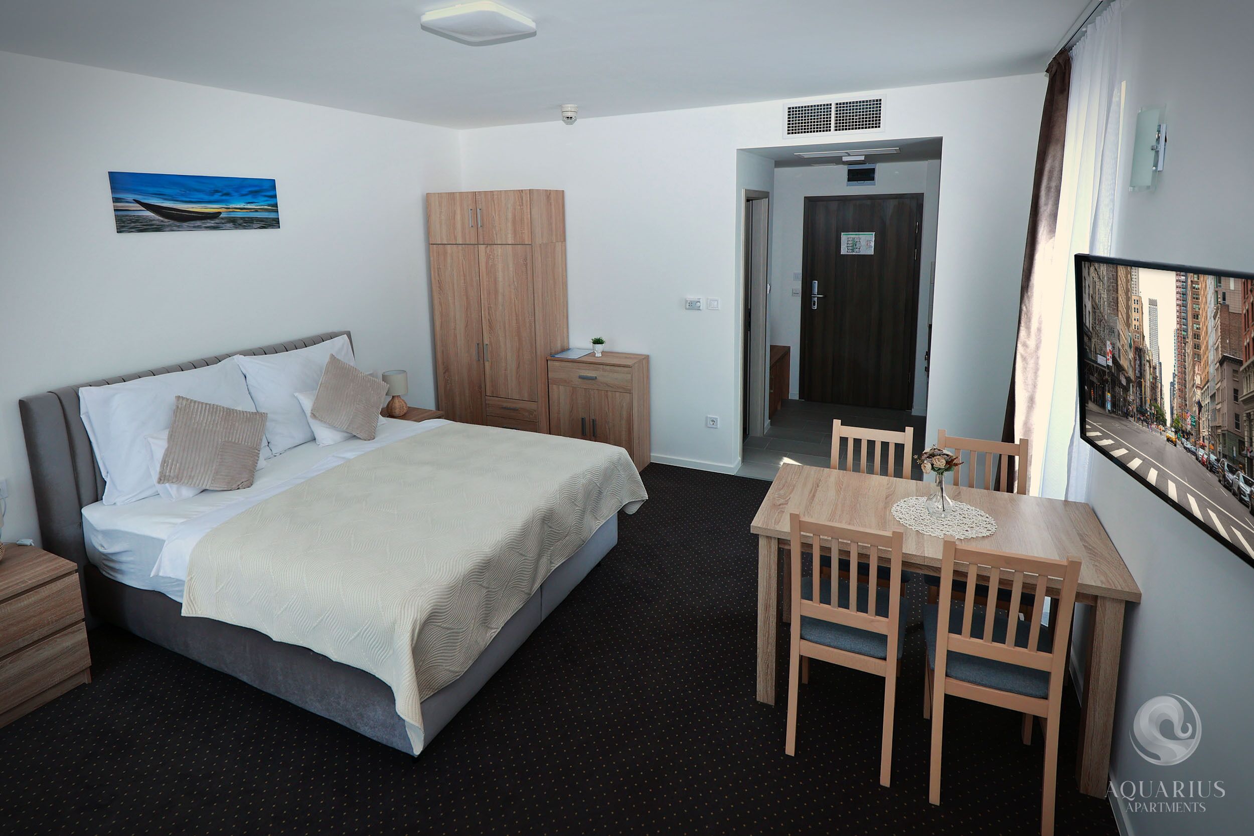 Habitación de hotel con cama, mesita de noche, armario y un área de comedor con sillas y una mesa.