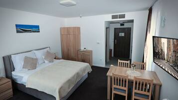 Habitación de hotel con cama, mesita de noche, armario y un área de comedor con sillas y una mesa.