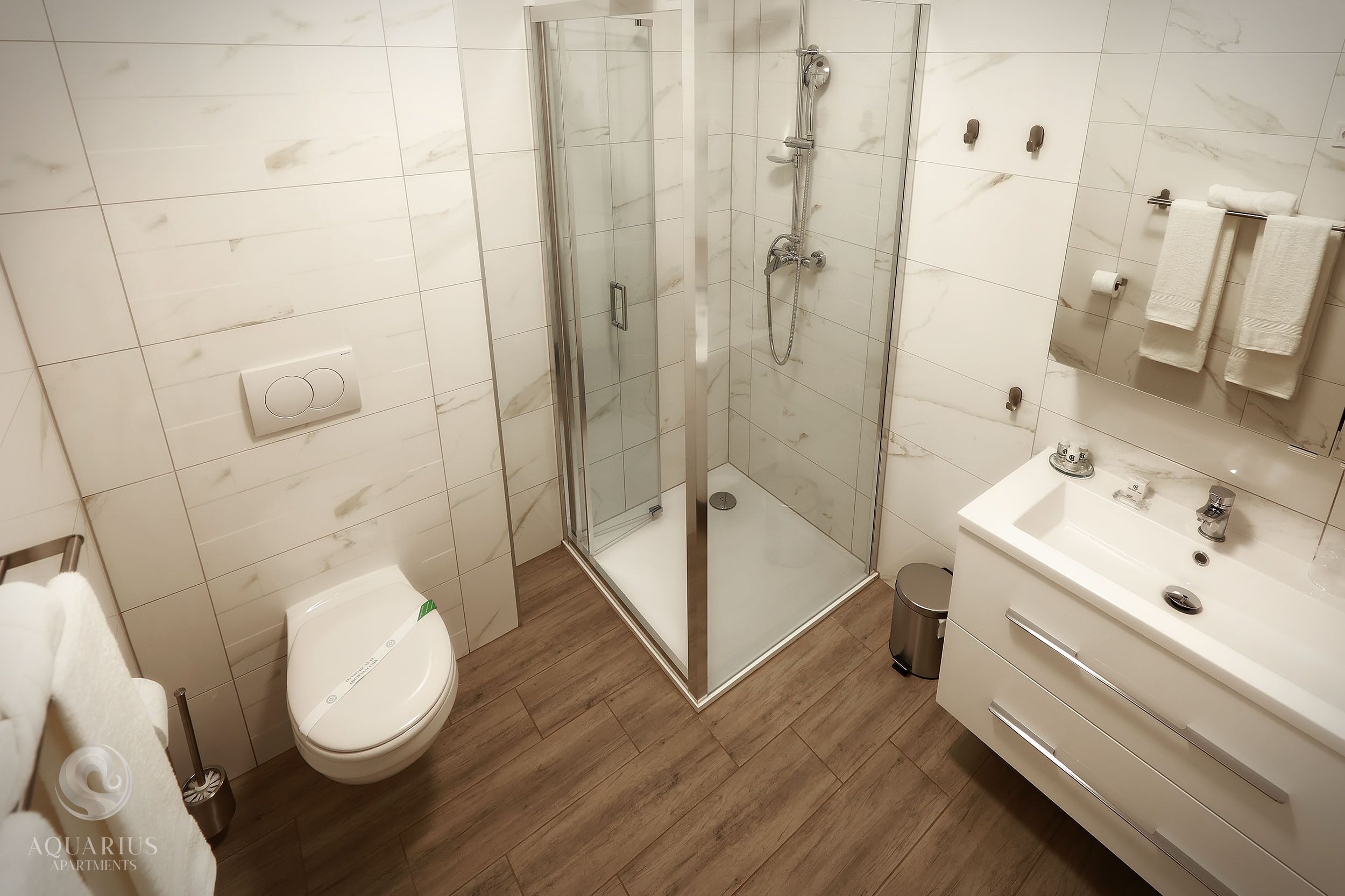 A modern bathroom with a glass-enclosed shower, a white toilet, and a vanity with a mirror and sink.