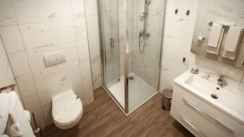 A modern bathroom with a glass-enclosed shower, a white toilet, and a vanity with a mirror and sink.