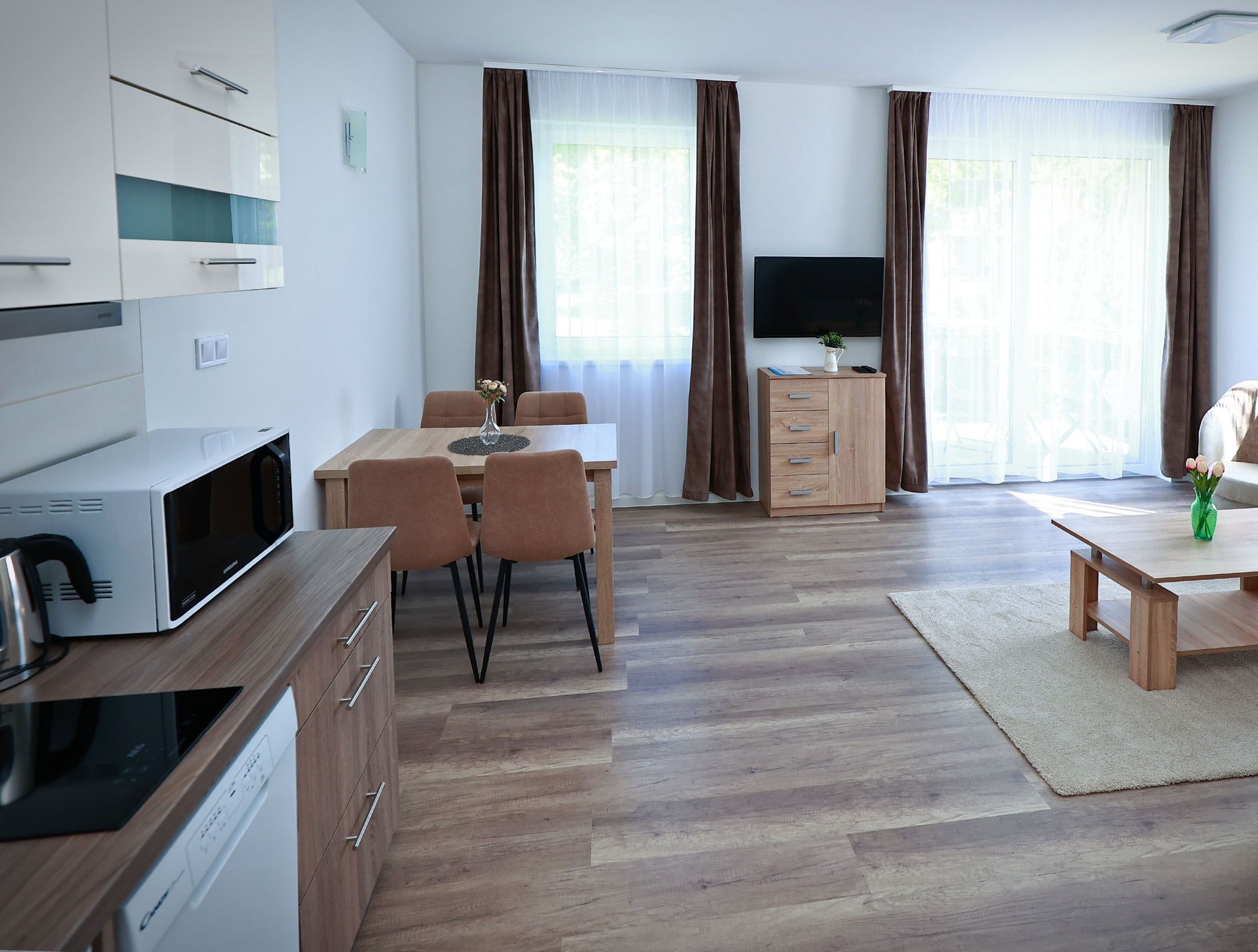 Una sala de estar moderna con comedor, armarios de madera, televisor de pantalla plana y sofá.