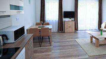 Una sala de estar moderna con comedor, armarios de madera, televisor de pantalla plana y sofá.
