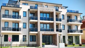 Ein mehrgeschossiges Gebäude mit Balkonen, mit der Aufschrift „AQUARIUS APARTMENTS“, das ein modernes architektonisches Design mit großen Fenstern und einem Flachdach aufweist.