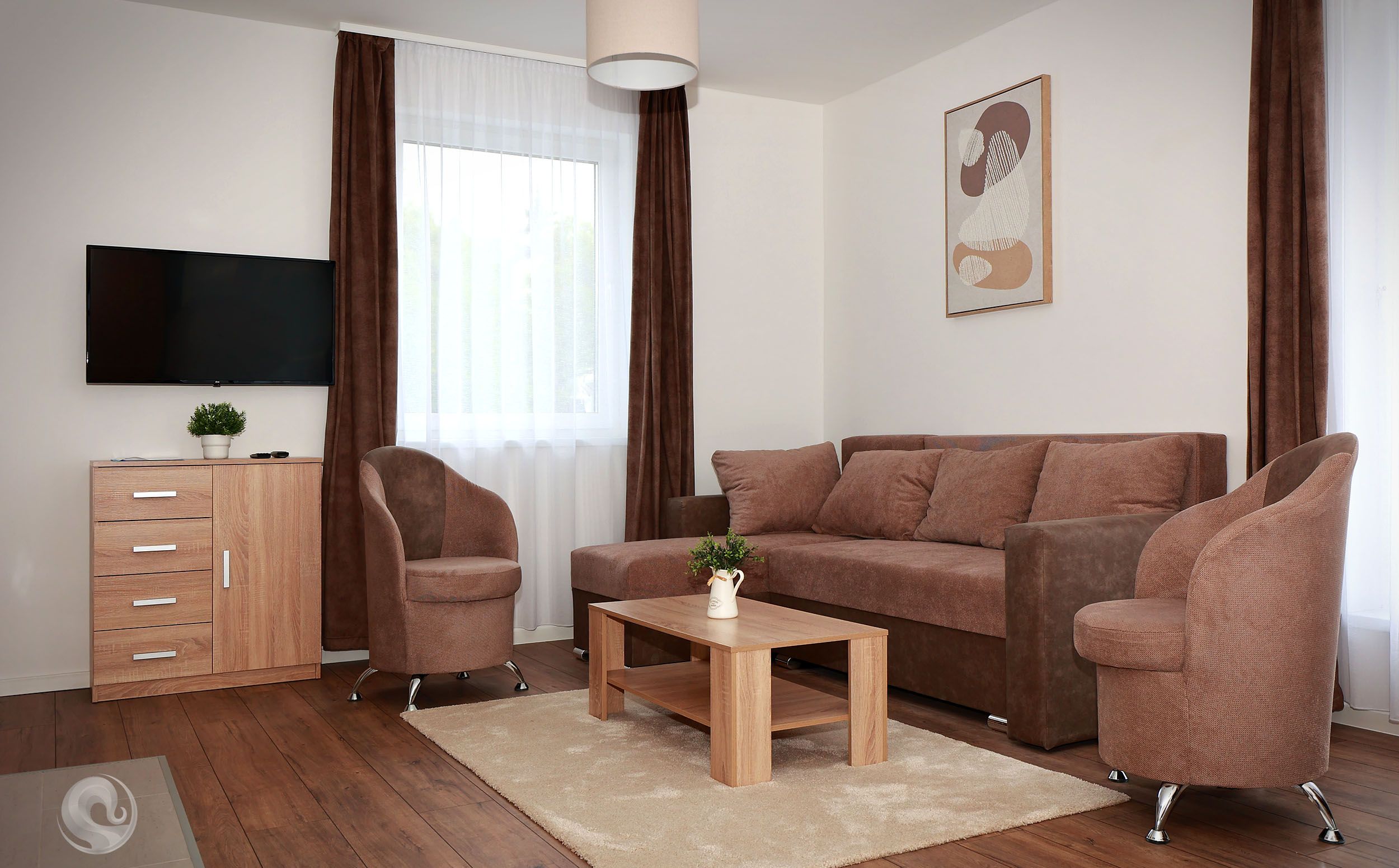 A modern living room with a sofa, two armchairs, a coffee table, and a TV mounted on the wall.