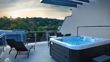 Eine Dachterrasse mit Whirlpool, Liegestühlen und Blick auf die Umgebung.