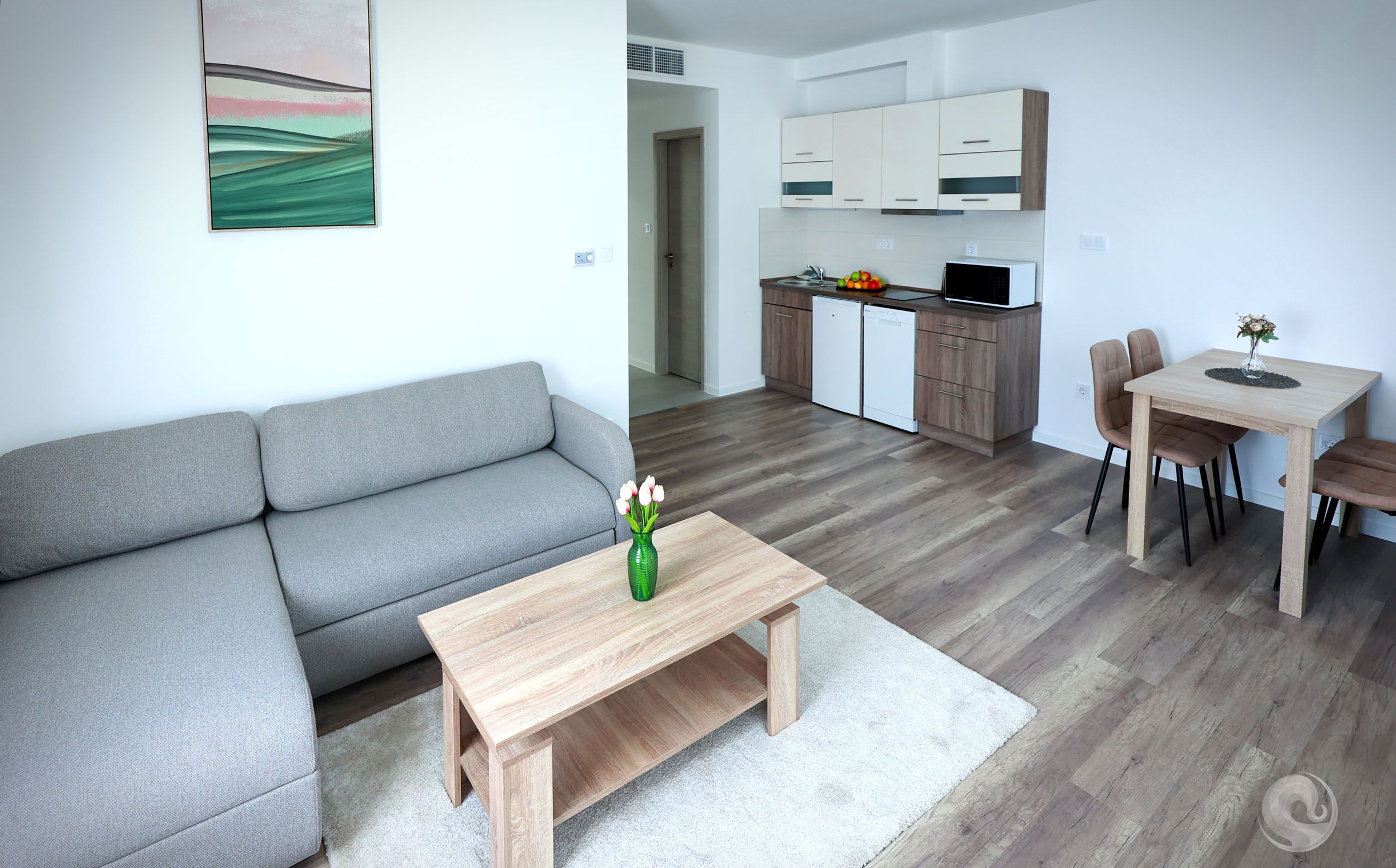 Un salon moderne avec un canapé gris, une table basse en bois et un coin repas comprenant une petite table et des chaises.