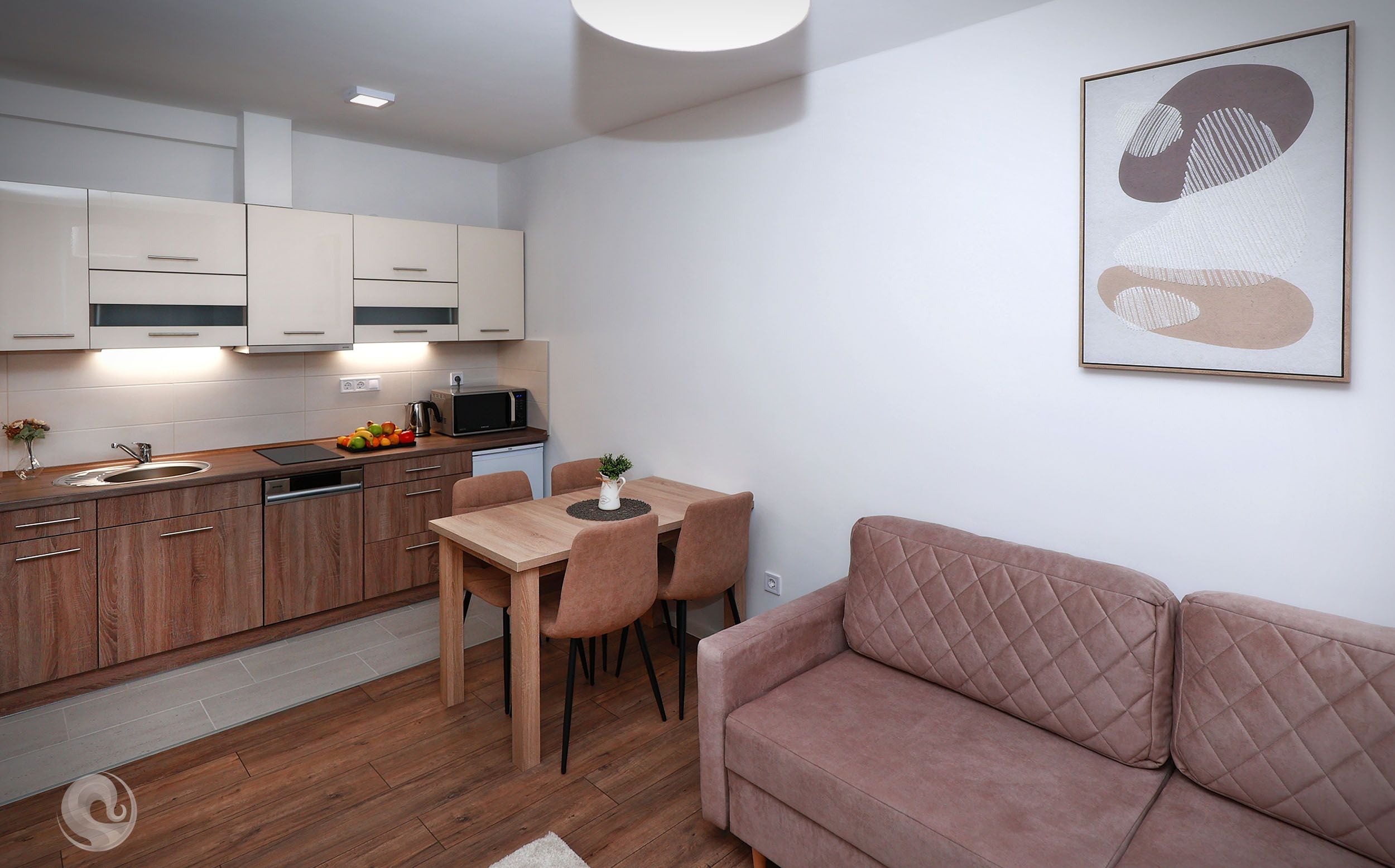 A modern kitchen with wooden cabinets, a dining area with a table and chairs, and a pink sofa in a living room.
