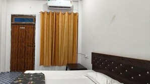 Un dormitorio con una cama, un armario de madera, una ventana con cortina y un aire acondicionado instalado en la pared.
