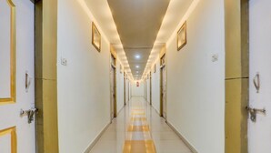 Un largo y estrecho pasillo de hotel con puertas a ambos lados, suelo de baldosas e iluminación en el techo.
