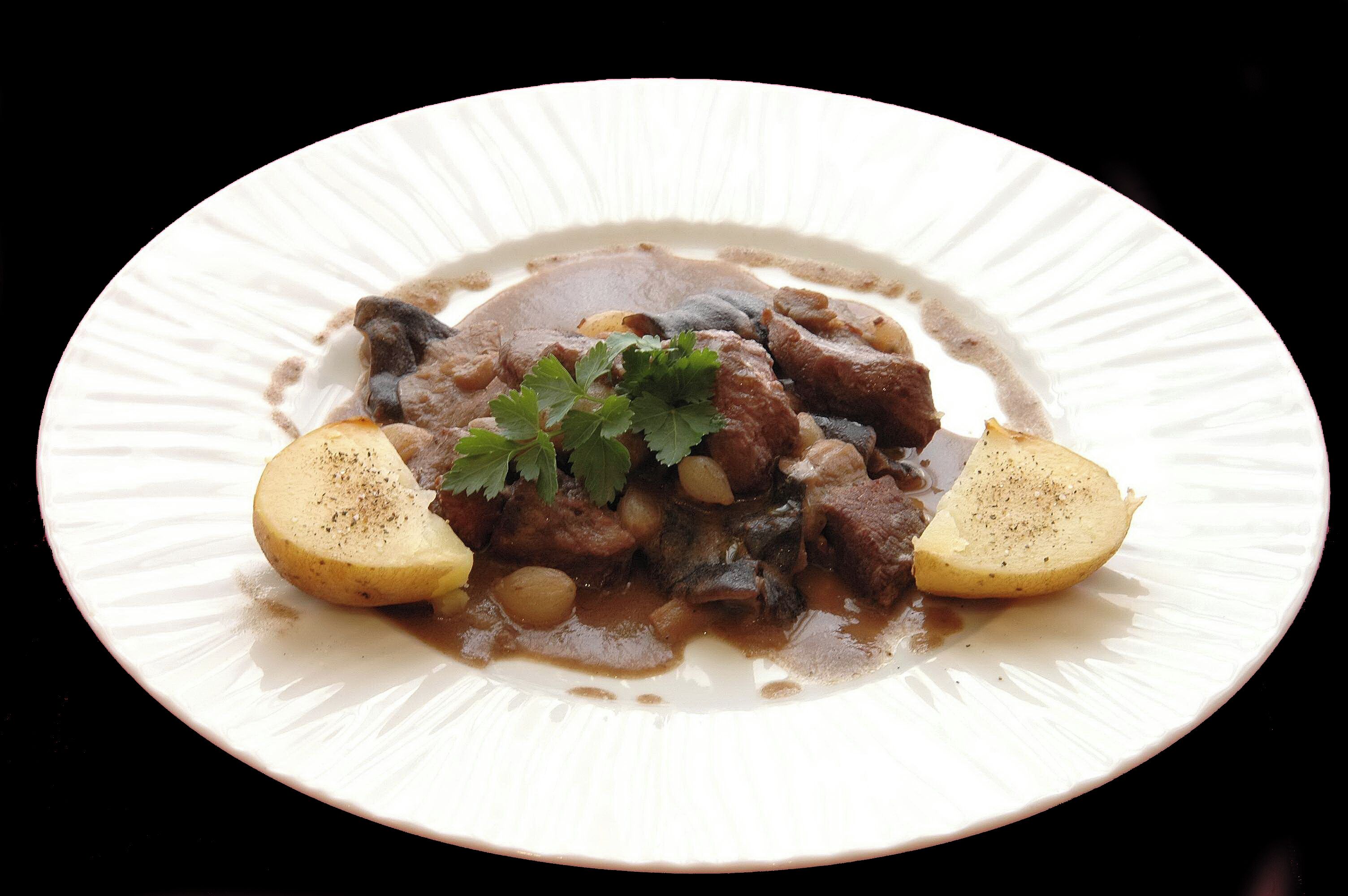 Plat de menjar amb un guisat, patates i una guarnició.